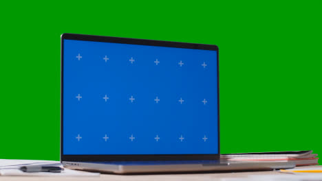 Blue-Screen-Laptop-With-Bills-On-Table-With-Green-Screen-Background