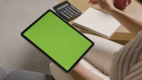 Frau,-Die-Ein-Digitales-Tablet-Und-Einen-Taschenrechner-Mit-Grünem-Bildschirm-Verwendet,-Um-Die-Haushaltsrechnungen-In-Der-Lebenshaltungskostenkrise-Zu-überprüfen