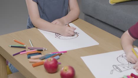 Close-Up-Of-Two-Children-At-Home-Colouring-In-Picture-At-Table