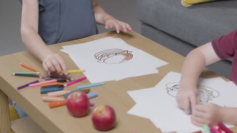 Primer-Plano-De-Dos-Niños-En-Casa-Coloreando-La-Imagen-En-La-Mesa-1