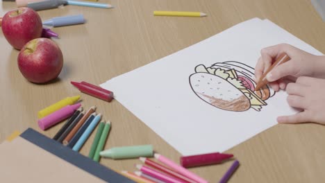 Close-Up-Of-Child-At-Home-Colouring-In-Picture-Of-Burger-At-Table
