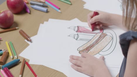 Close-Up-Of-Child-At-Home-Colouring-In-Picture-Of-Hot-Dog-At-Table-1