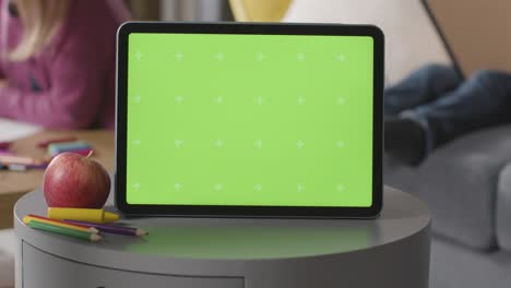 Nahaufnahme-Eines-Digitalen-Greenscreen-Tablets-Mit-Kindern,-Die-Im-Hintergrund-Malen-Und-Lesen-1