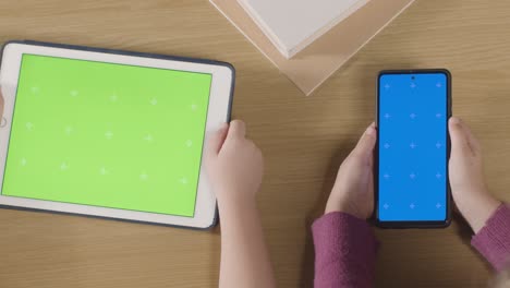 Overhead-Shot-Of-Children-Using-Green-Screen-Digital-Tablet-And-Blue-Screen-Mobile-Phone-On-Table-At-Home-2