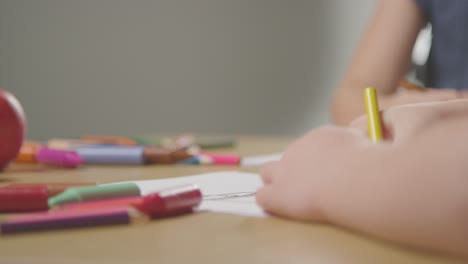 Primer-Plano-De-Dos-Niños-En-Casa-Dibujando-Y-Coloreando-Imágenes-En-La-Mesa