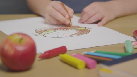 Primer-Plano-De-Un-Niño-En-Casa-Coloreando-La-Imagen-De-Una-Hamburguesa-En-La-Mesa-Con-Manzana-Fresca-En-Primer-Plano