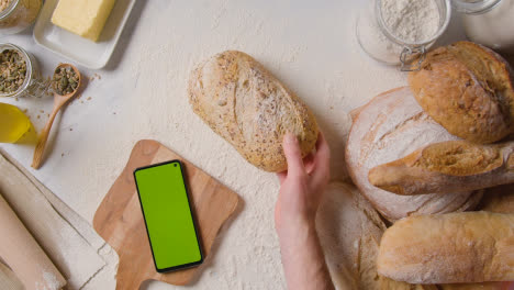 Fotografía-Cenital-De-Hogazas-De-Pan-Recién-Horneadas-En-Una-Superficie-De-Trabajo-De-Mármol-Con-Un-Teléfono-Móvil-De-Pantalla-Verde-1