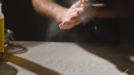 Low-Key-Shot-Of-Person-In-Apron-Rubbing-Hands-With-Flour-Before-Baking-With-Ingredients