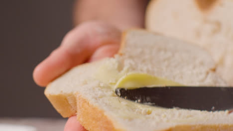 Estudio-De-Cerca-De-Una-Persona-Untando-Con-Mantequilla-Una-Rebanada-De-Pan-Fresco-Con-Un-Cuchillo