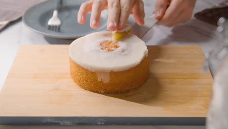 Persona-Cortando-Una-Rebanada-De-Pastel-Casero-De-Limón-En-Un-Plato-En-La-Superficie-De-Trabajo-De-La-Cocina