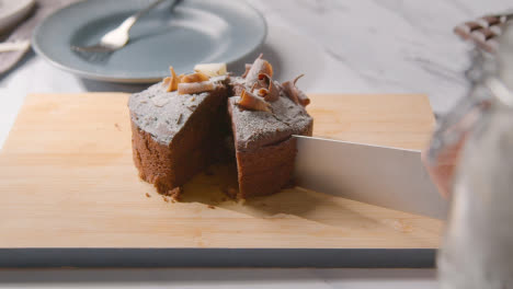 Person-Cutting-Slice-Of-Homemade-Chocolate-Cake-Onto-Plate-On-Kitchen-Work-Surface-1