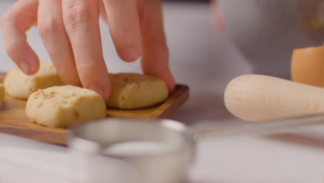 Person-Putting-Homemade-Shortbread-Cookies-Onto-Tray-On-Kitchen-Work-Surface