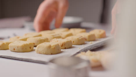 Person-Putting-Down-Tray-Of-Homemade-Shortbread-Cookies-On-Kitchen-Work-Surface-1