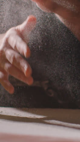 Vertical-Video-Low-Key-Shot-Of-Person-In-Apron-Rubbing-Hands-With-Flour-Before-Baking