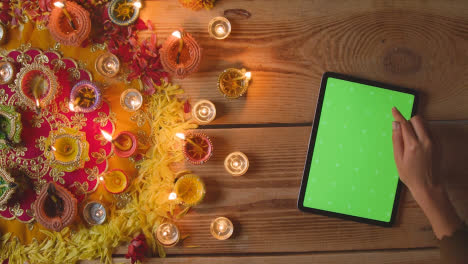 Fotografía-Cenital-De-Una-Persona-Que-Usa-Una-Tableta-Digital-De-Pantalla-Verde-Con-Lámparas-Encendidas-Celebrando-El-Festival-De-Diwali