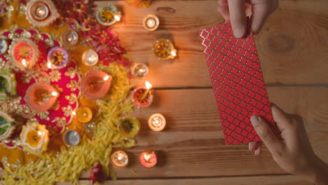 Overhead-Shot-Of-Person-Receiving-Gift-Of-Money-With-Burning-Lamps-Celebrating-Festival-Of-Diwali-2