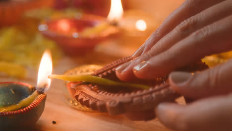 Close-Up-Of-Person-Adding-Oil-And-Lighting-Lamp-Celebrating-Festival-Of-Diwali