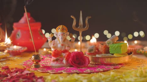 Person,-Die-Räucherstäbchen-Neben-Der-Ganesh-Statue-Auf-Einem-Geschmückten-Tisch-Hält,-Der-Das-Diwali-Fest-Feiert