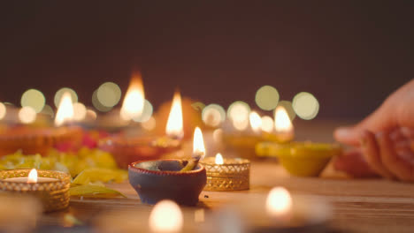 Person,-Die-Eine-Diya-Lampe-Auf-Einem-Tisch-Anzündet,-Der-Dekoriert-Ist,-Um-Das-Fest-Von-Diwali-1-Zu-Feiern
