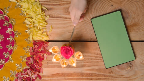 Person-Holding-Five-Wick-Lamp-On-Table-With-Green-Screen-Digital-Tablet-In-Festival-Of-Diwali