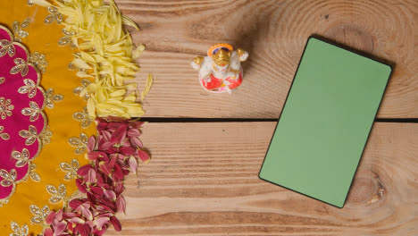 Hand-Putting-Statue-Of-Ganesh-On-Table-With-Green-Screen-Digital-Tablet-In-Festival-Of-Diwali