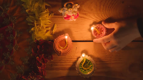 Mano-Poniendo-Lámpara-Diya-En-La-Mesa-Decorada-Para-El-Festival-De-Diwali-Con-Estatua-De-Ganesh-1