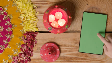 Clay-Pot-With-Lights-Being-Used-To-Celebrate-Indian-Wedding-Diwali-Or-Navratri-On-Decorated-Table-With-Digital-Tablet-1