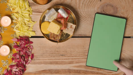 Overhead-Shot-Of-Indian-Sweets-In-Bowl-On-Table-Decorated-To-Celebrate-Festival-Of-Diwali-With-Digital-Tablet