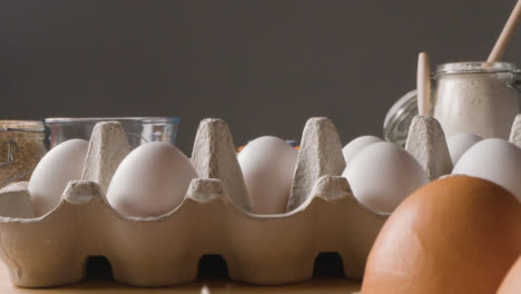 Foto-De-Estudio-De-Ingredientes-Y-Utensilios-Para-Hornear-En-La-Encimera-De-La-Cocina-Con-Una-Persona-Recogiendo-Huevos-3