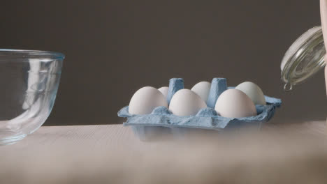 Foto-De-Estudio-De-Ingredientes-Para-Hornear-Y-Utensilios-En-La-Encimera-De-La-Cocina-Con-Una-Persona-Recogiendo-Huevos-5