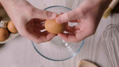 Overhead-Shot-Of-Kitchen-Utensils-On-Kitchen-Worktop-With-Person-Cracking-Egg-Into-Bowl