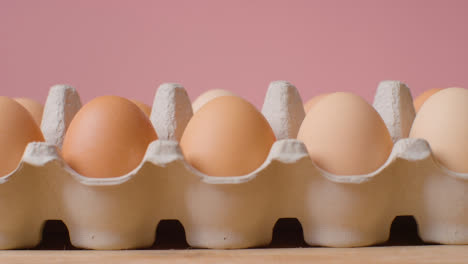 Studio-Shot-Of-Open-Cardboard-Egg-Boxes-Against-Pink-Background