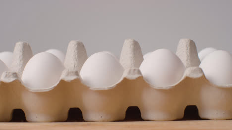 Studio-Shot-Of-Person-Choosing-From-Open-Cardboard-Boxes-Containing-White-Eggs-Against-Grey-Background