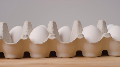 Studio-Shot-Of-Person-Choosing-From-Open-Cardboard-Box-Containing-White-Eggs-Against-Grey-Background