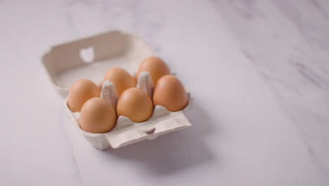 Studio-Shot-Of-Open-Cardboard-Egg-Box-Against-Marble-Work-Surface-Background