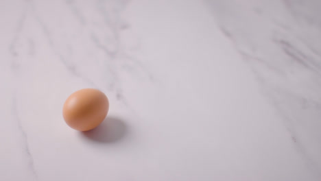 Studioaufnahme-Eines-Einzelnen-Braunen-Eies-Auf-Marmorarbeitsfläche-Im-Hintergrund