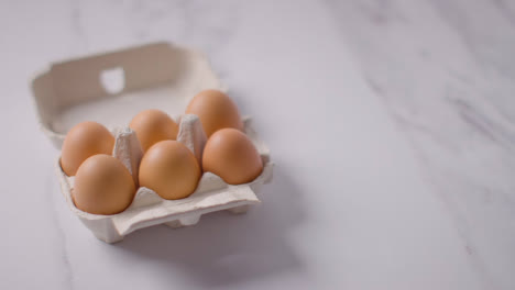 Studio-Shot-Of-Open-Cardboard-Egg-Box-Against-Marble-Work-Surface-Background-1