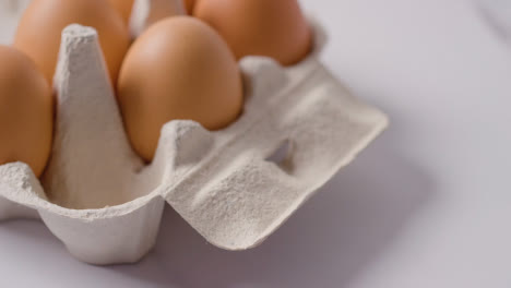 Studio-Shot-Of-Person-Choosing-Egg-From-Open-Cardboard-Box-On-Marble-Work-Surface-Background-5