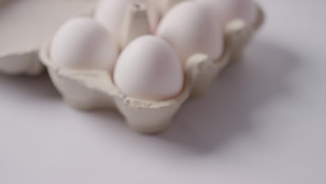 Studio-Shot-Of-Person-Picking-Up-Box-Of-White-Eggs-On-Marble-Work-Surface-Background-1