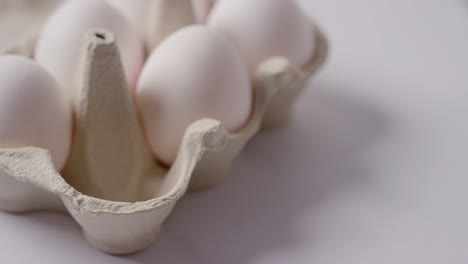 Studio-Shot-Of-Person-Choosing-White-Egg-From-Open-Cardboard-Box-On-Marble-Work-Surface-Background-1