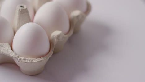 Studio-Shot-Of-Person-Picking-Up-Box-Of-White-Eggs-On-Marble-Work-Surface-Background-2