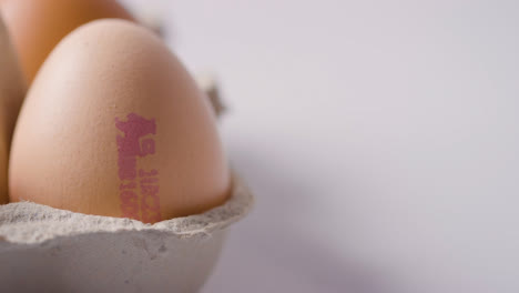 Studio-Shot-Of-Open-Box-Of-Brown-Eggs-With-Quality-Control-Stamp-On-Work-Surface-Background