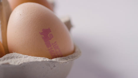 Studio-Shot-Of-Person-Choosing-Brown-Egg-With-Quality-Control-Stamp-From-Open-Box