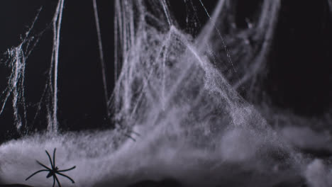 Gruselige-Halloween-Spinnenweben-Und-Spinnen-Vor-Schwarzem-Hintergrund