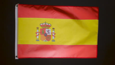 Studio-Shot-Of-Flag-Of-Spain-Flying-Against-Black-Background