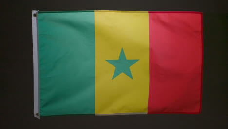 Studio-Shot-Of-Flag-Of-Senegal-Flying-Against-Black-Background