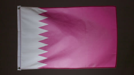 Studioaufnahme-Der-Flagge-Von-Katar,-Die-Vor-Schwarzem-Hintergrund-Zusammenbricht