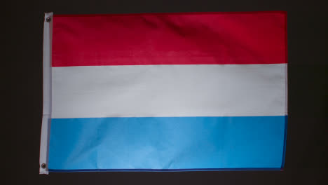 Studioaufnahme-Der-Flagge-Der-Niederlande,-Die-Vor-Schwarzem-Hintergrund-Zusammenbricht