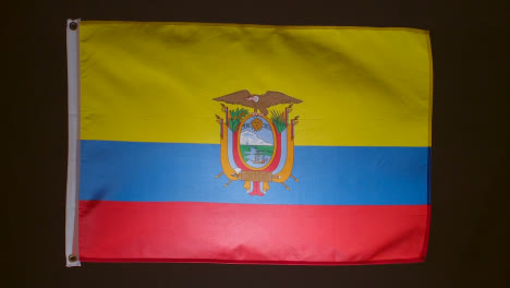 Studio-Shot-Of-Flag-Of-Ecuador-Flying-Against-Black-Background