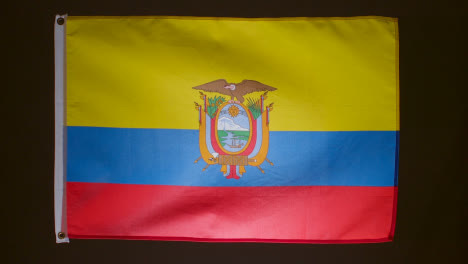 Studioaufnahme-Der-Flagge-Ecuadors,-Die-Vor-Schwarzem-Hintergrund-Herunterfällt
